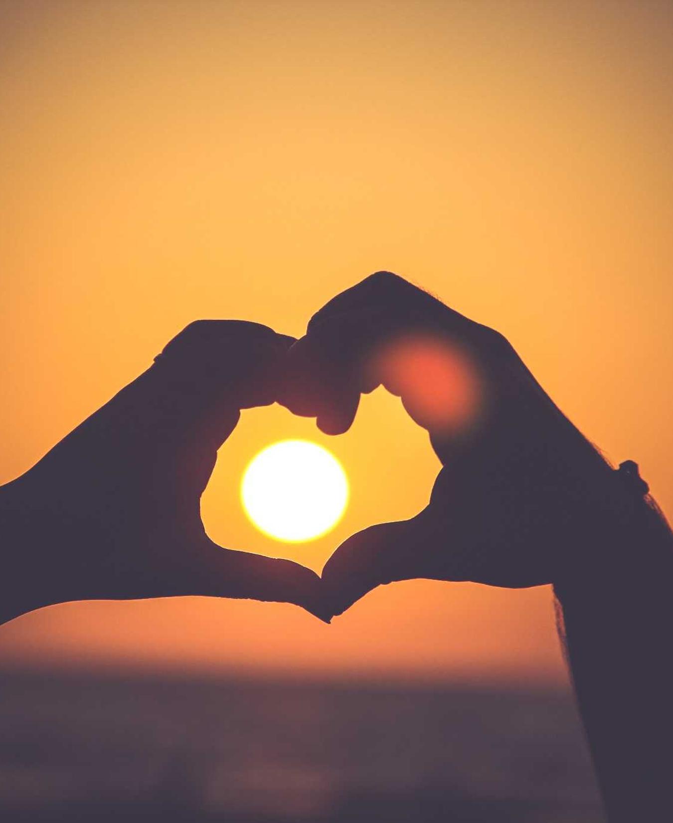 Hands making a heart at sunset